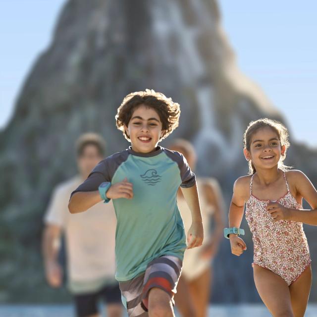 Kids in swim suits running ahead of their parents at Universal's Volcano Bay in Orlando, Florida