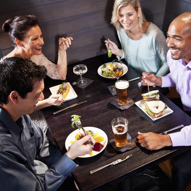 Two couples eating, drinking and talking in restaurant.