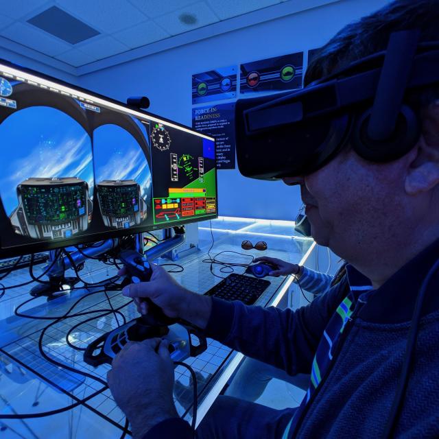 A man operates a joystick of a virtual reality flight simulator computer at Orlando Science Center.