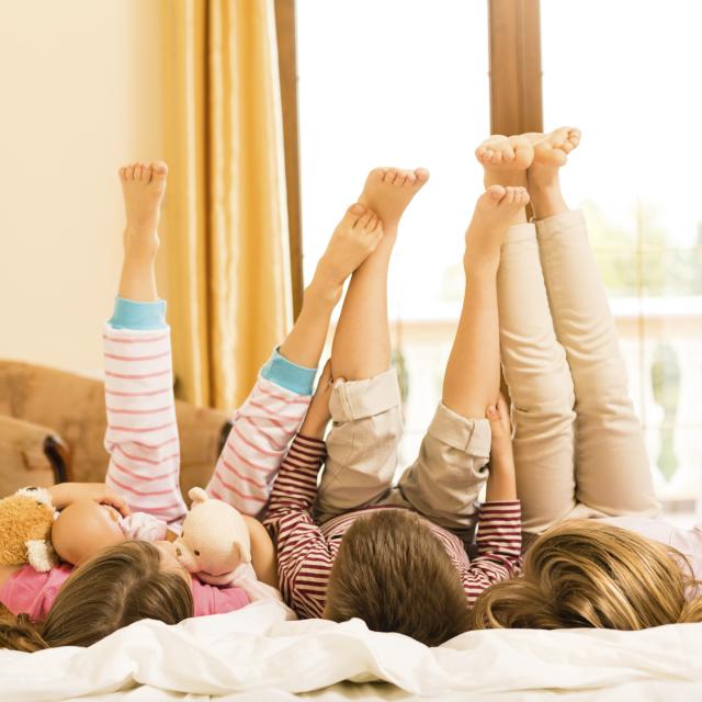 Children lying down on a bed with legs in the air