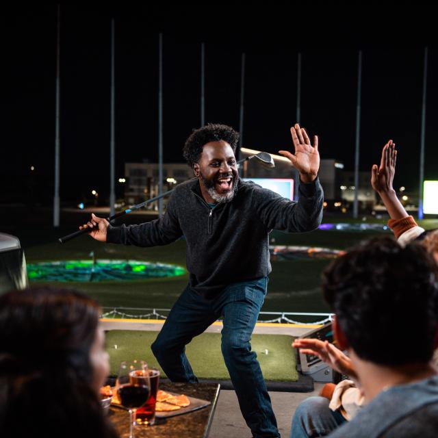 Man going for high-five after golf shot at Topgolf