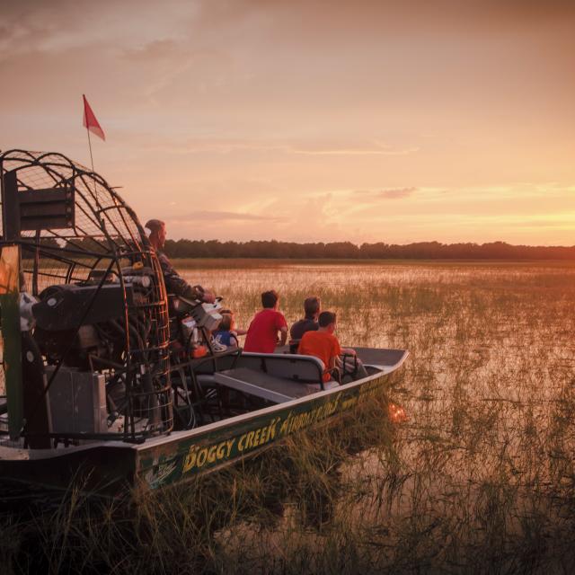 A group enjoys the sunset as they watch from an airboat tour at Boggy Creek