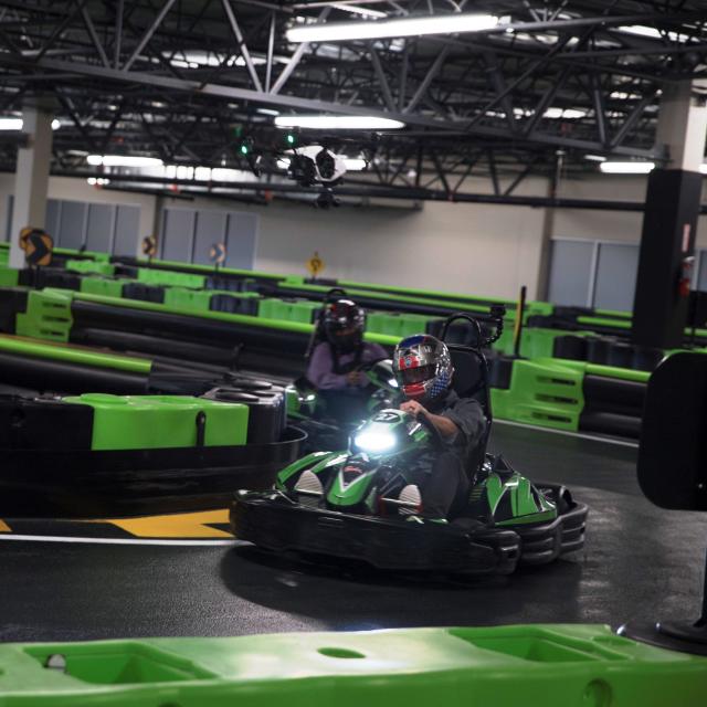 A driver in a go-kart rounds a turn, while being closely followed at Andretti Indoor Karting & Games in Orlando, Florida.
