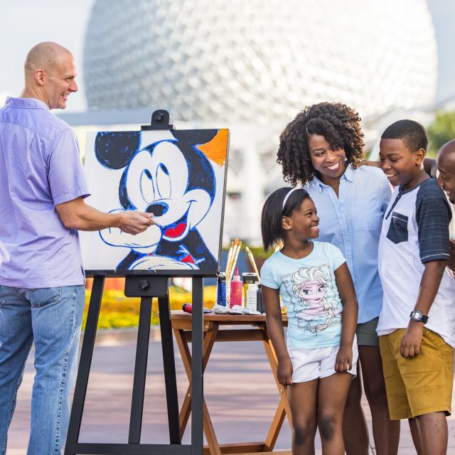 A family watches an artist paint at International Festival of the Arts at Epcot.