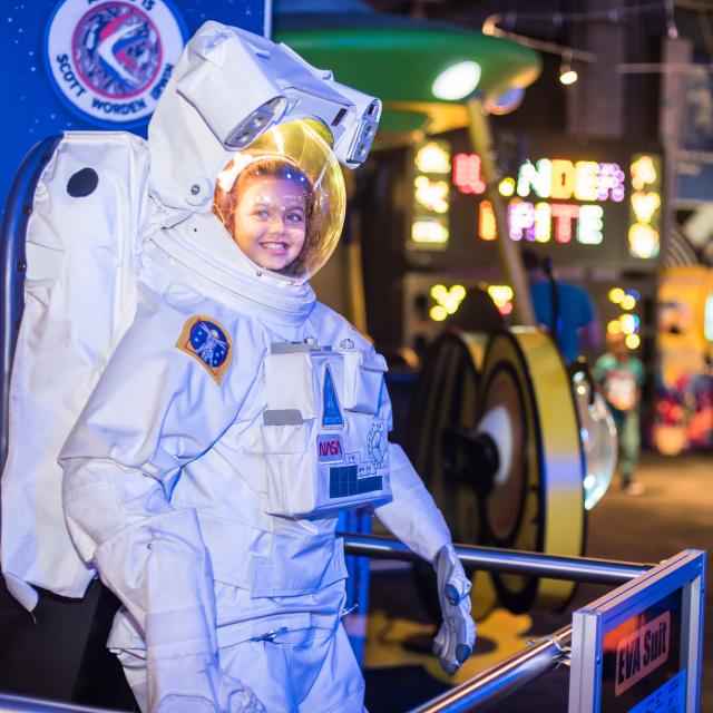 A girl tries on an astronaut suit at WonderWorks in Orlando.