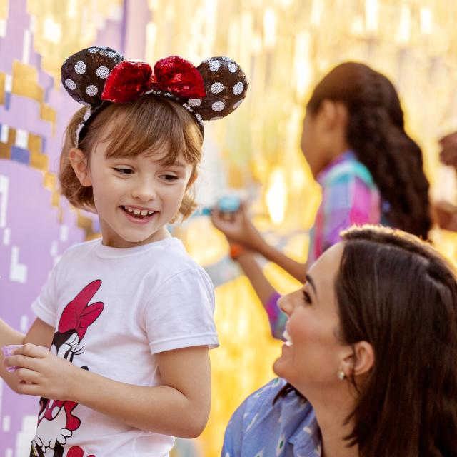 A young girl painting while her mom watches at the Epcot® 2023 Festival of the Arts