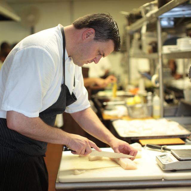 Chef James Petrakis preparing a dish in the kitchen at The Ravenous Pig restaurant