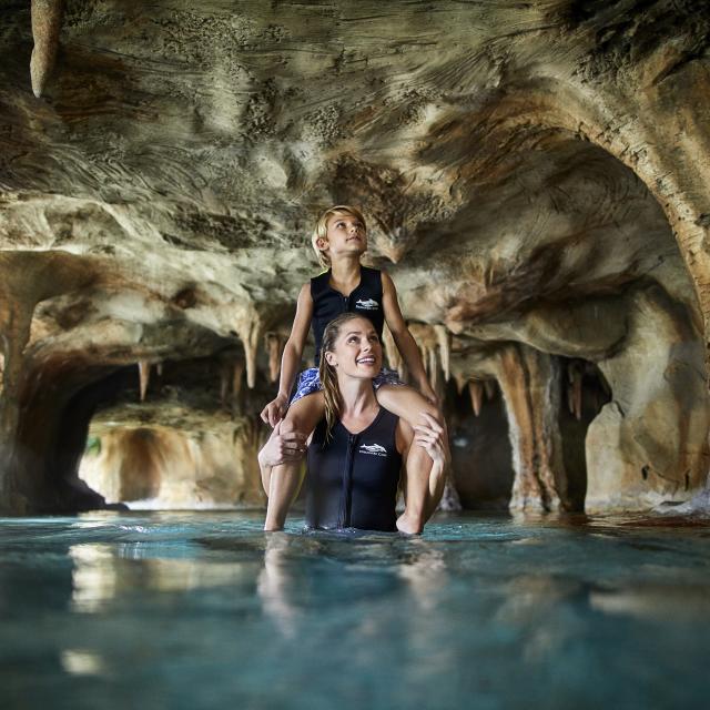 A mother with her son on her shoulders in a cave at Discovery Cove