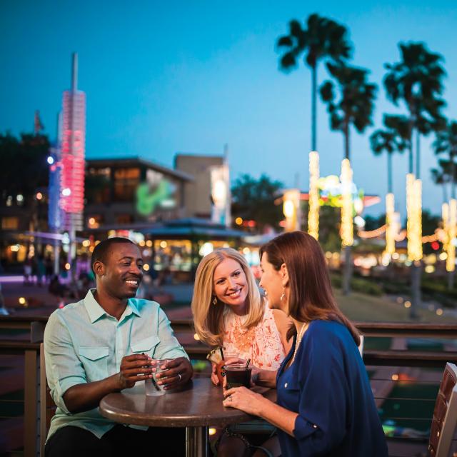 Three people sitting at a table, having drinks at Universal CityWalk at night