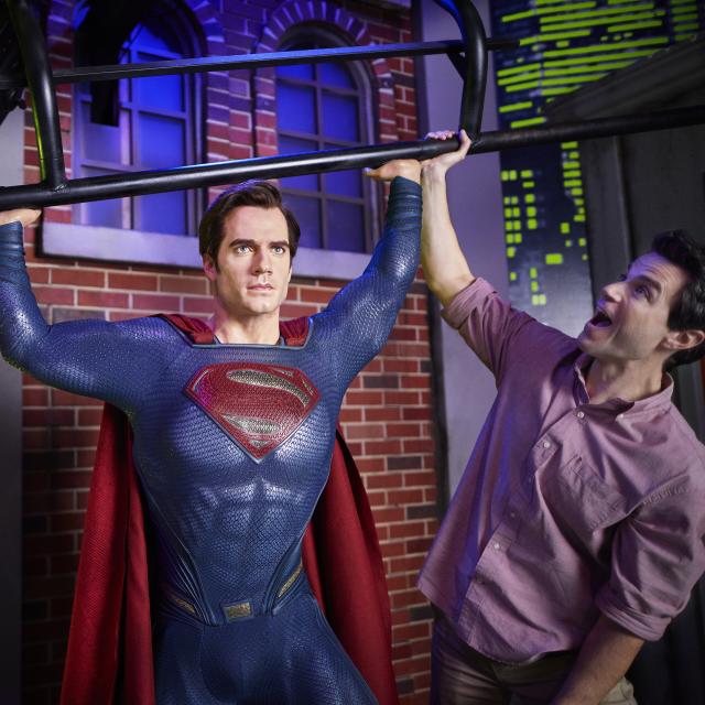 A father and son posing with Superman at Madame Tussauds in ICON Park.