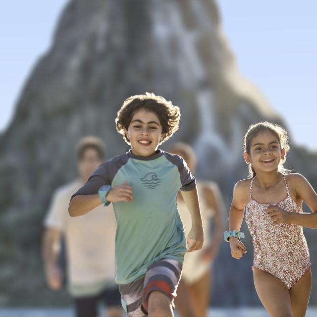 Kids in swim suits running ahead of their parents at Universal's Volcano Bay