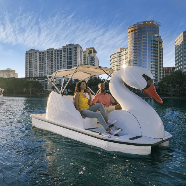 Una pareja explorando el lago Eola en un barco cisne en el centro de Orlando
