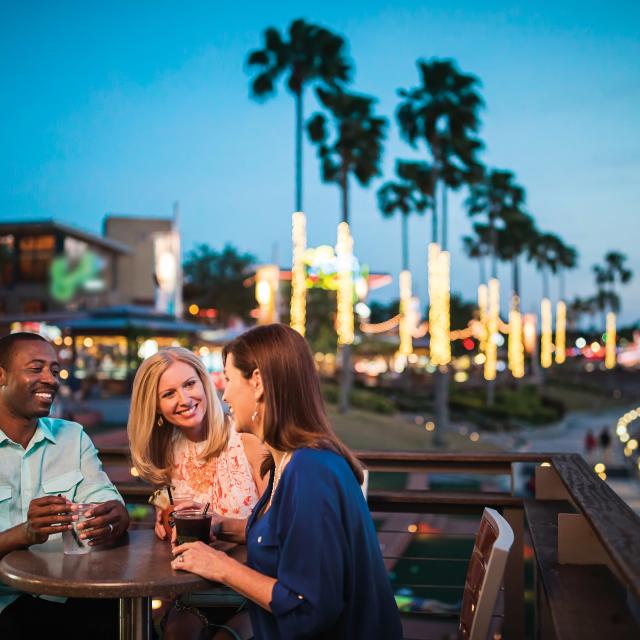 Three people sitting at a table, having drinks at Universal CityWalk at night