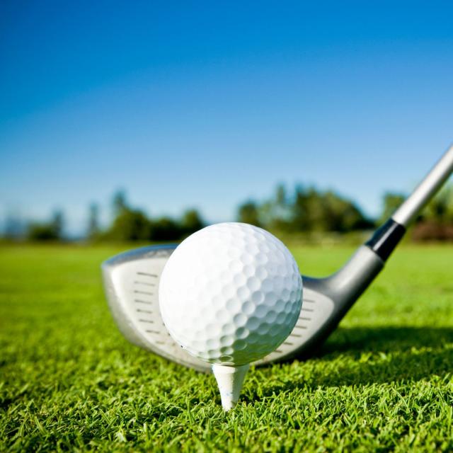 A close up of a golf ball on a tee and a golf club
