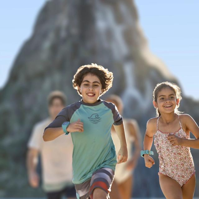 Kids in swim suits running ahead of their parents at Universal's Volcano Bay