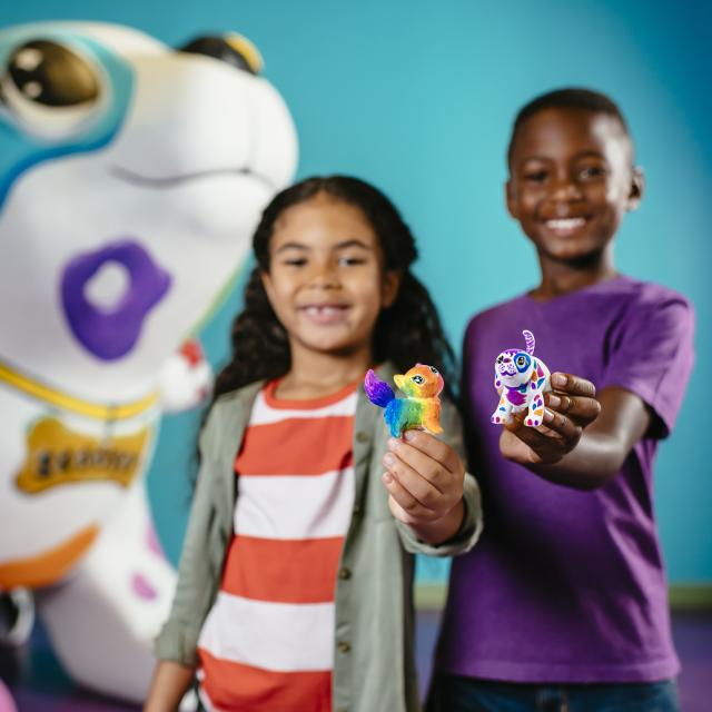 A boy and a girl show off their Scribble Scrubbies creations at Crayola Experience Orlando