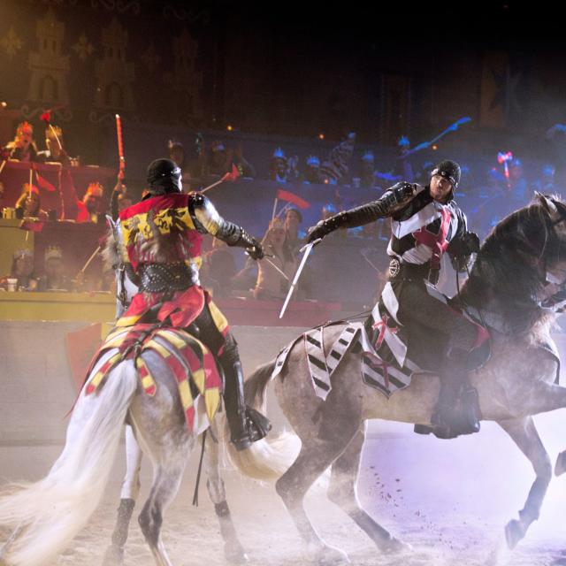 Two knights on horseback battle with swords at Medieval Times Dinner & Tournament