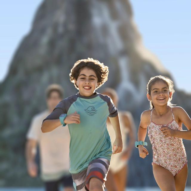 Kids in swim suits running ahead of their parents at Universal's Volcano Bay in Orlando, Florida