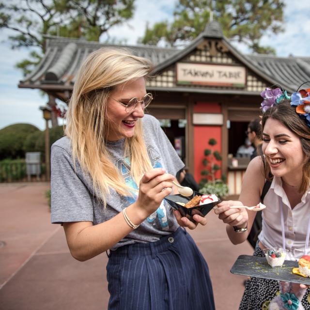 Two women enjoy food at the Epcot International Festival of the Arts