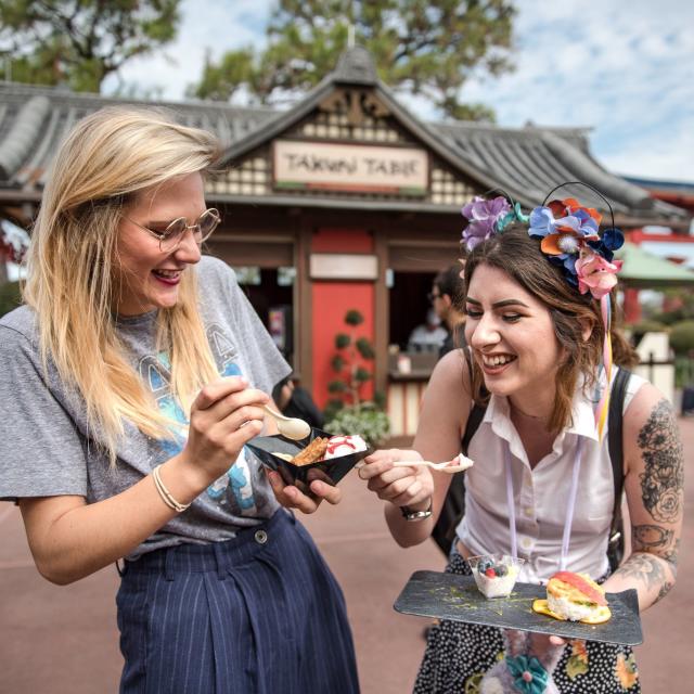 Two women enjoy food at the Epcot International Festival of the Arts