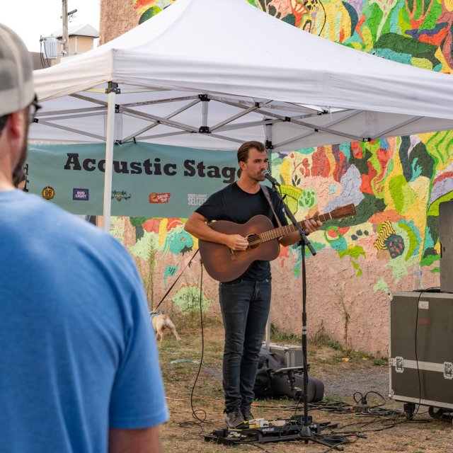 A musician playing his guitar at an outdoor festival.