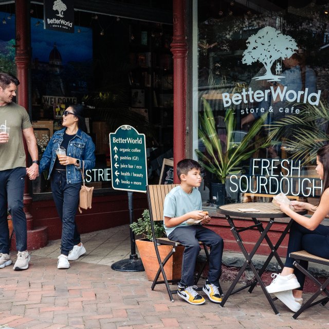 Couple shopping and two kids easting at a table outside a store in a downtown