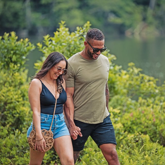 A couple holding hands while walking along a lakeside path.