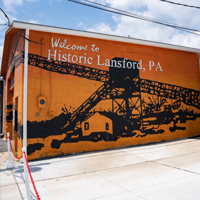 Orange building with a coal mining mural and the words “Welcome to Historic Lansford, PA” painted on the side.