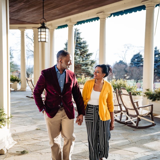 A couple holding hands while walking on a veranda at a Pocono resort