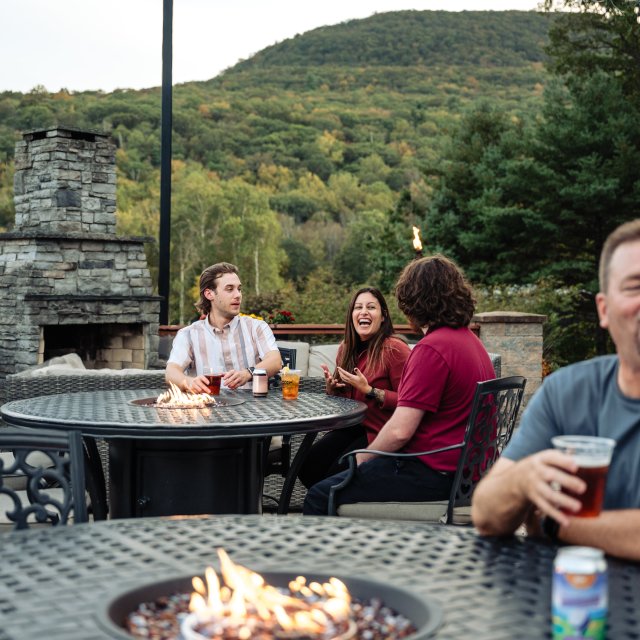 A group of people sitting at an outdoor patio table, enjoying cocktails together.
