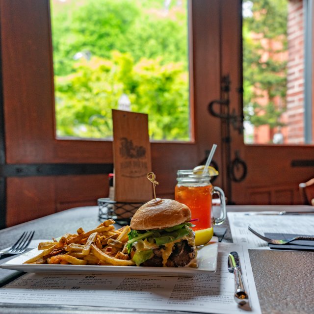 Delicious sandwich with French fries, pickle and a beverage.