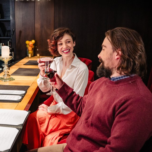 A couple toasting with wine glasses before the start of their meal.