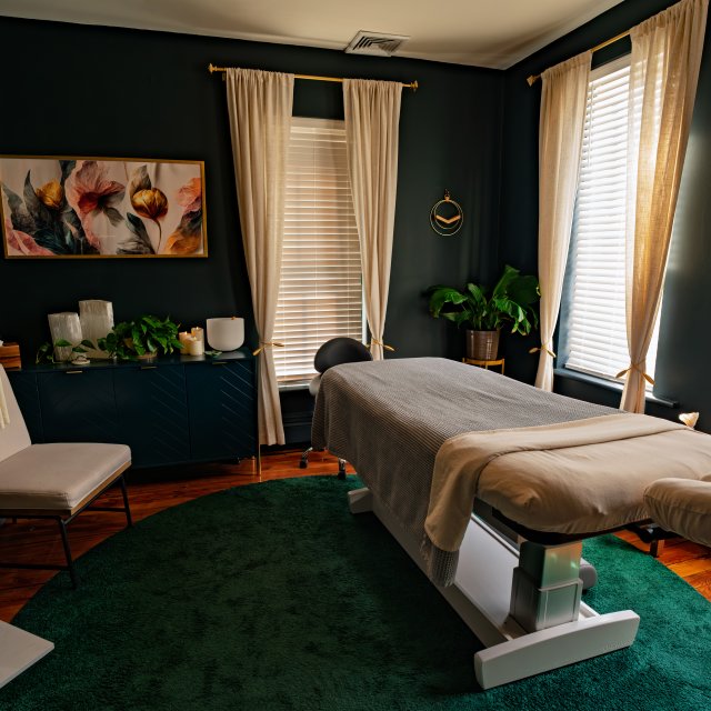 A massage room with a massage table and a robe hanging nearby.