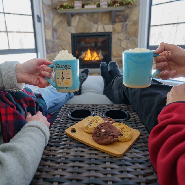 A couple drinking hot coco and cookies in front of the fireplace