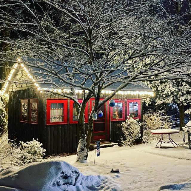 Exterior of a cabin at Babbling Brook Cottages in Dingmans Ferry, PA lit up on a winter night.