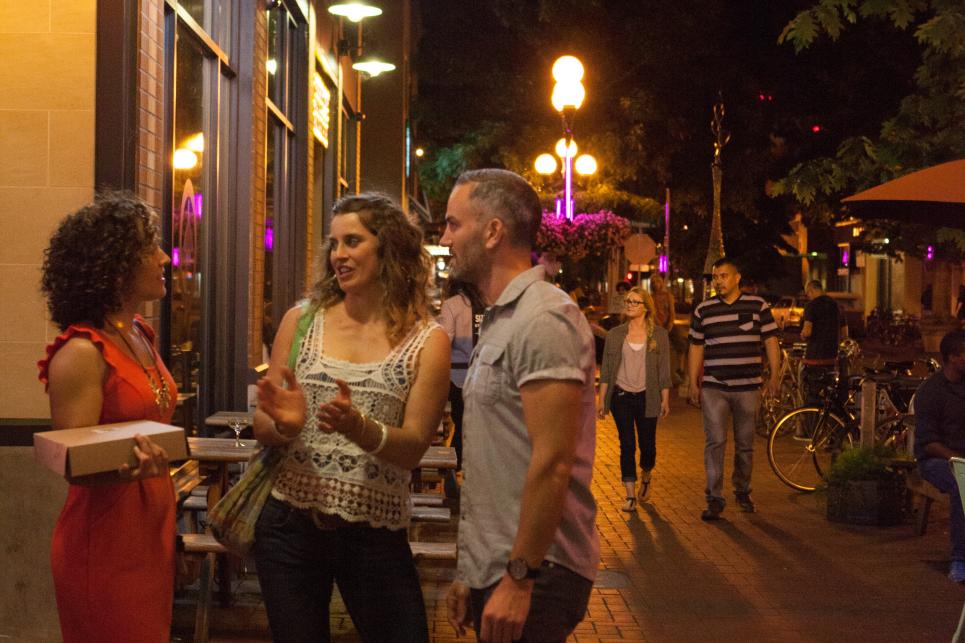 People with food to go outside the Barn Light coffee house in downtown at night.