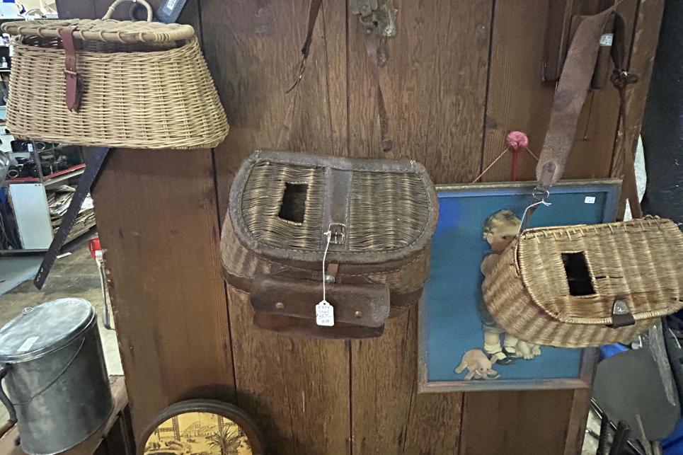 Under a sign American Cowboy, three fishing creels hang on the wall.