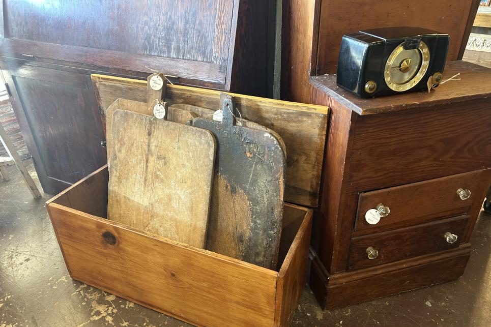 Multiple large rustic bread boards are displayed in a wood box.