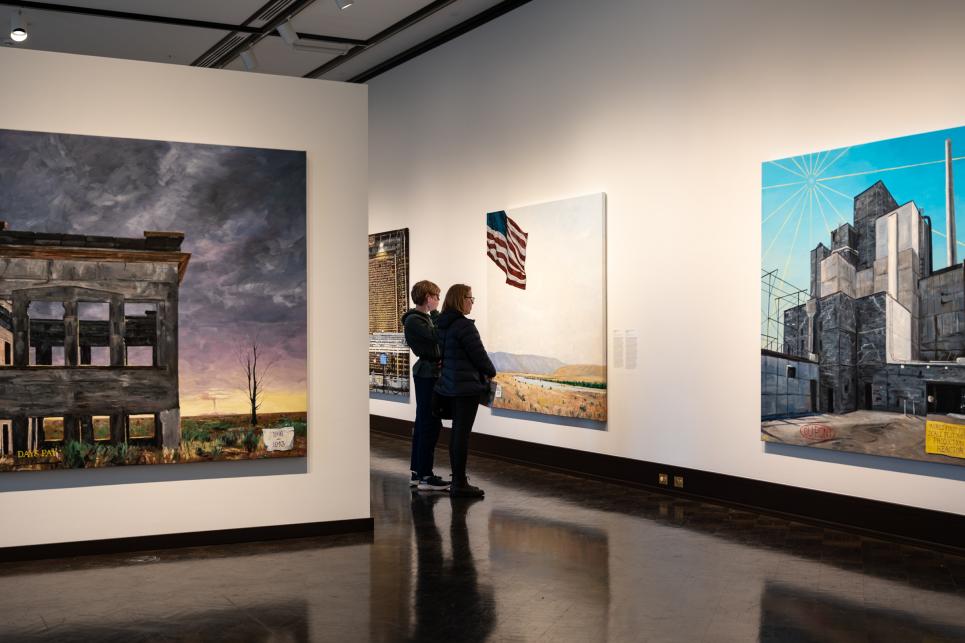 People look at large art pieces in the gallery.
