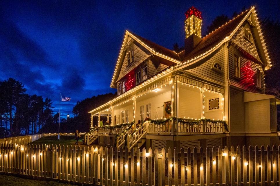 A white Victorian-style house is trimmed in twinkle lights.