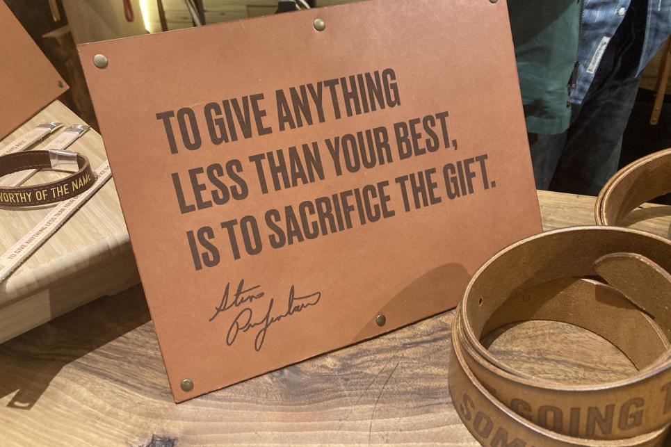 A leather sign is embossed with the quote by Steve Prefontaine "To give anything less than your best, is to sacrifice the gift."