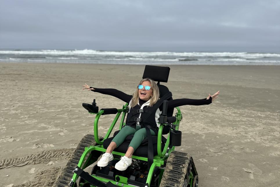 Kirstin using a green track chair on the beach.