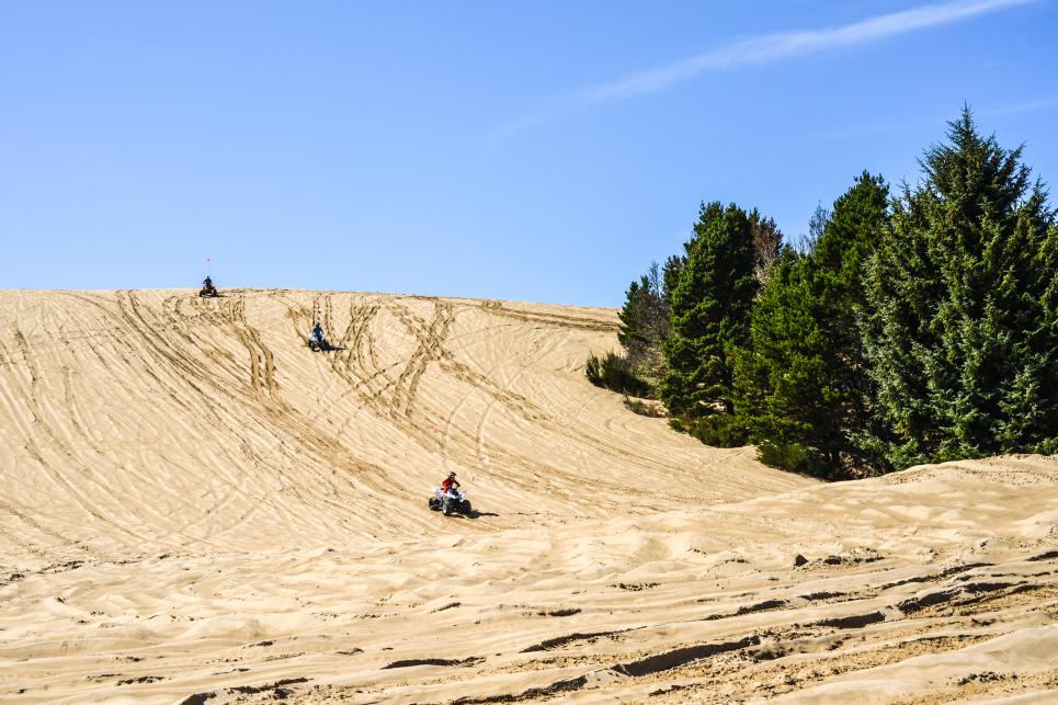 Three ATV drivers cruise down the dunes.