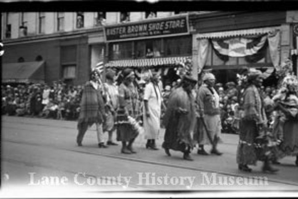 A black and white photo of Indigenous Peoples in regalia for a parade in 1926 down the streets of Eugene.