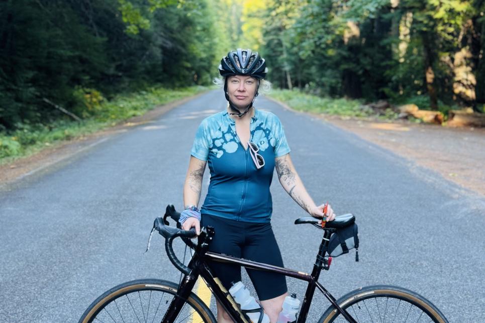 A cyclist stands with her bicycle on the yellow lines of the Aufderheide.