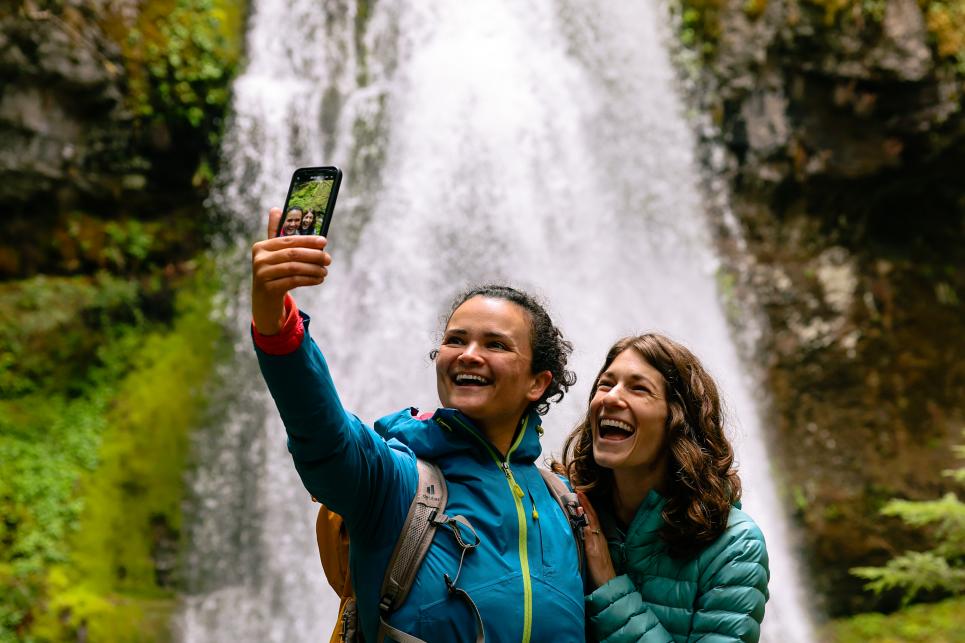 A couple takes a selfie in front of a waterfall