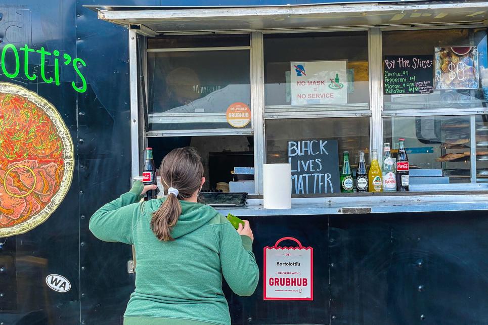 Person ordering at the window of a pizza food truck.