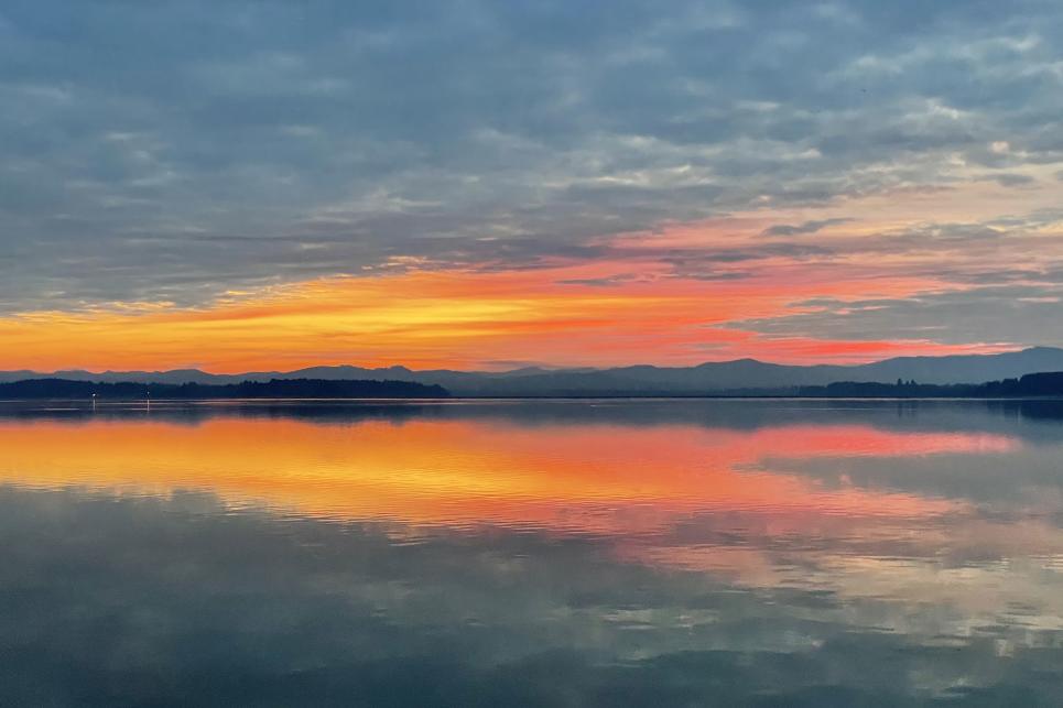 A pink and orange sunset over a lake with mountains in the background