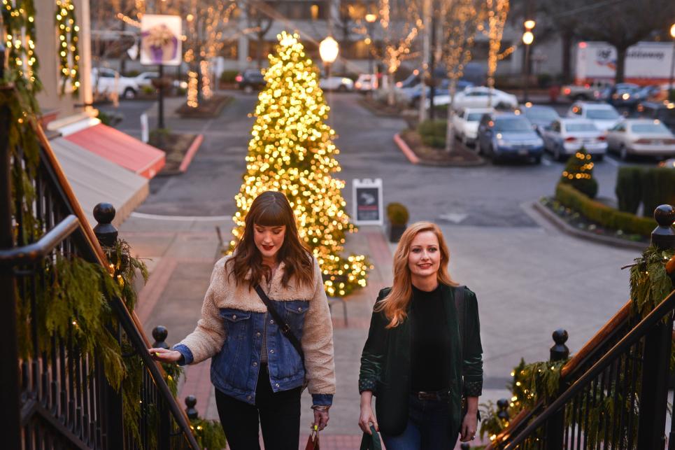 Shoppers coming up staircase at dusk with Christmas Tree