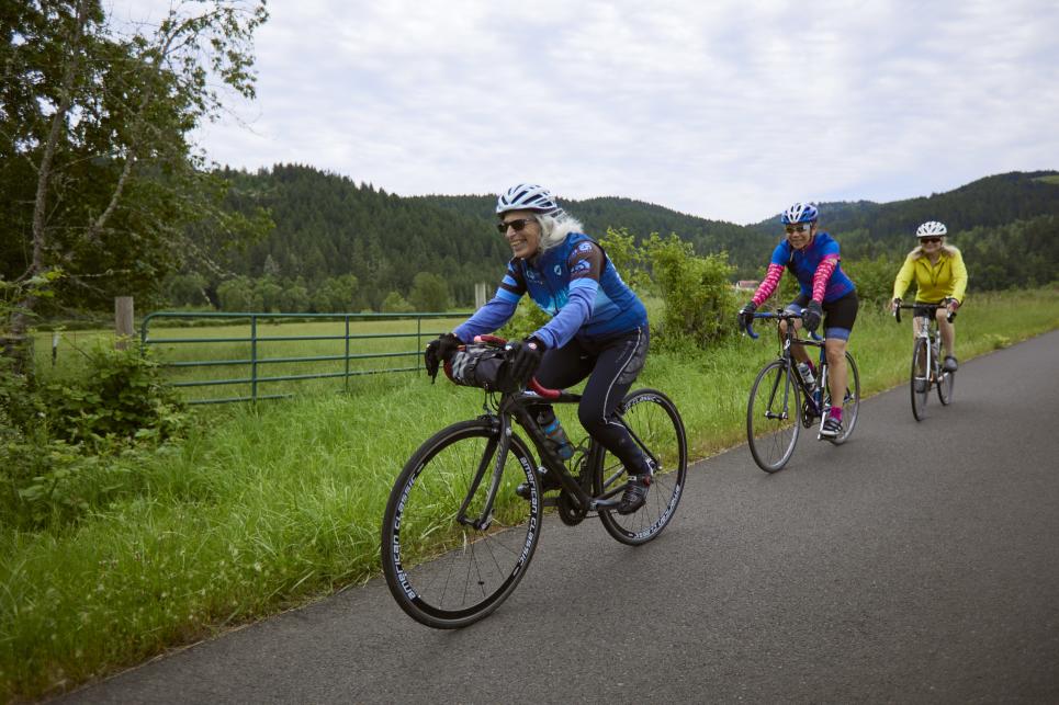Three people riding single file along a country road.